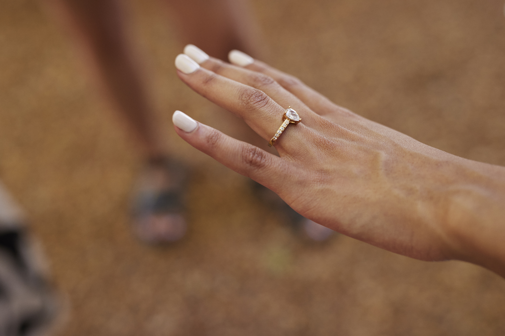 Close-up of a person's left hand showing an engagement ring with a prominent diamond and a matching wedding band on their ring finger