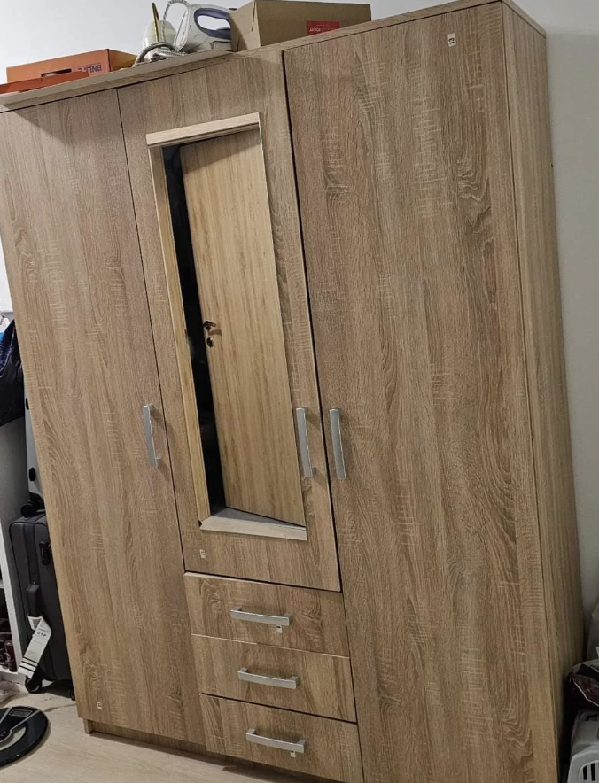 Wooden wardrobe with a mirrored door, two doors on either side, and four drawers beneath the mirror in a tidy, organized room