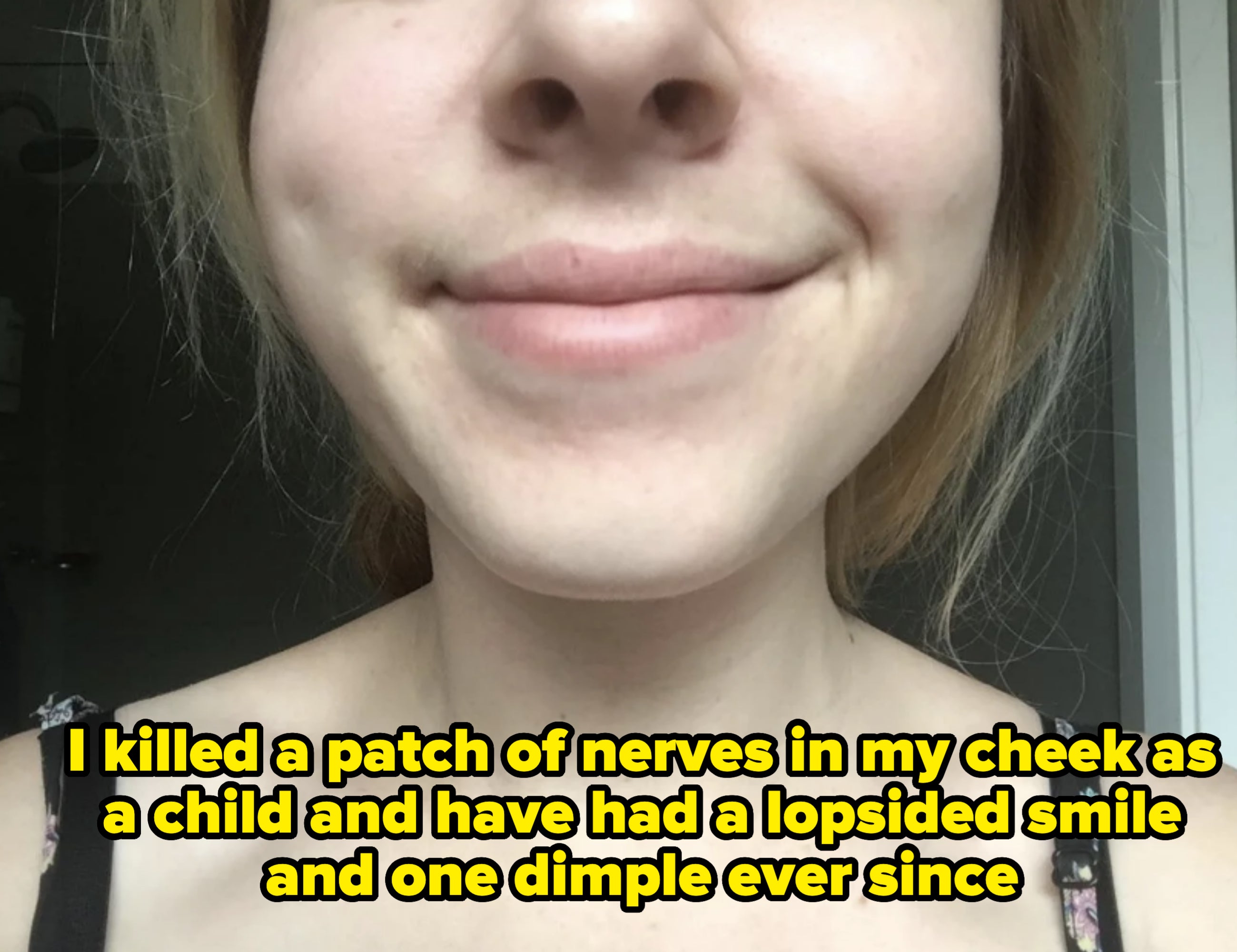A person with light hair is smiling slightly, showing dimples. Their face is partially visible in the image