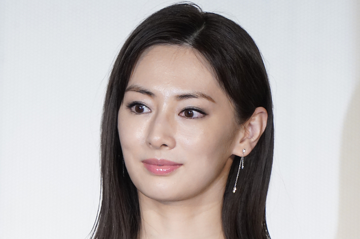 女性が黒のドレスを着てカメラに向かって微笑んでいます。