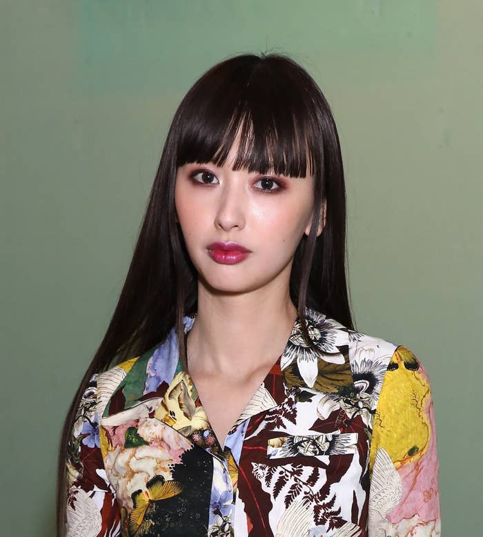 齋藤飛鳥がカジュアルな花柄シャツを着てポーズをとっている。