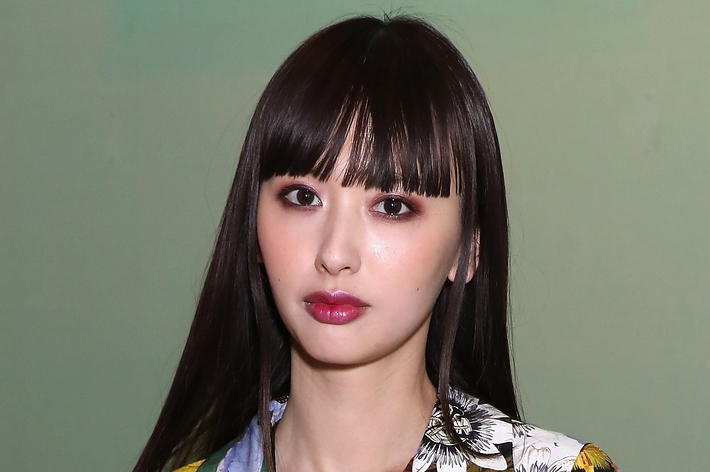 齋藤飛鳥がカジュアルな花柄シャツを着てポーズをとっている。