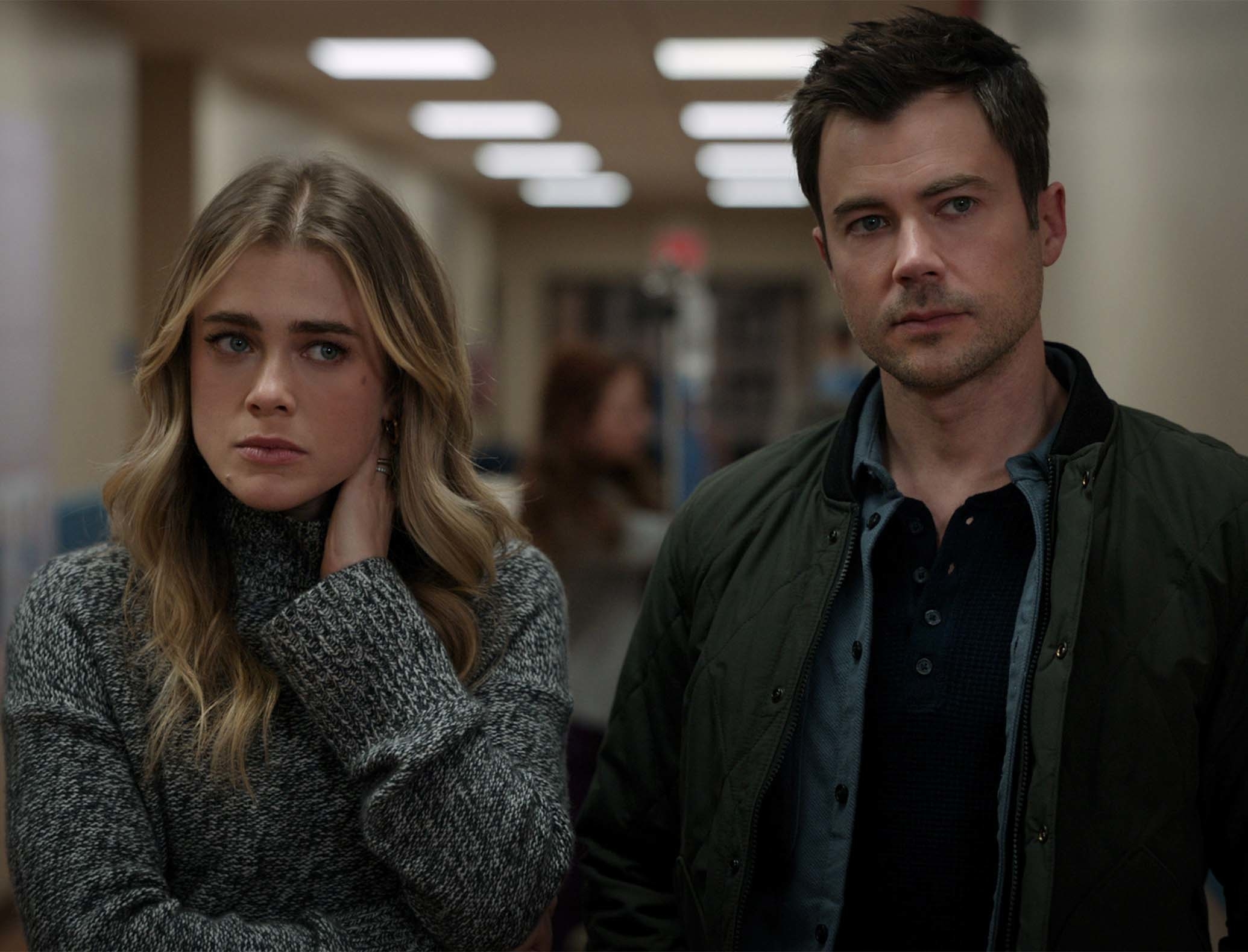 Melissa Roxburgh and Matt Long in a hallway scene, Melissa wearing a cozy sweater and Matt in a casual jacket and shirt