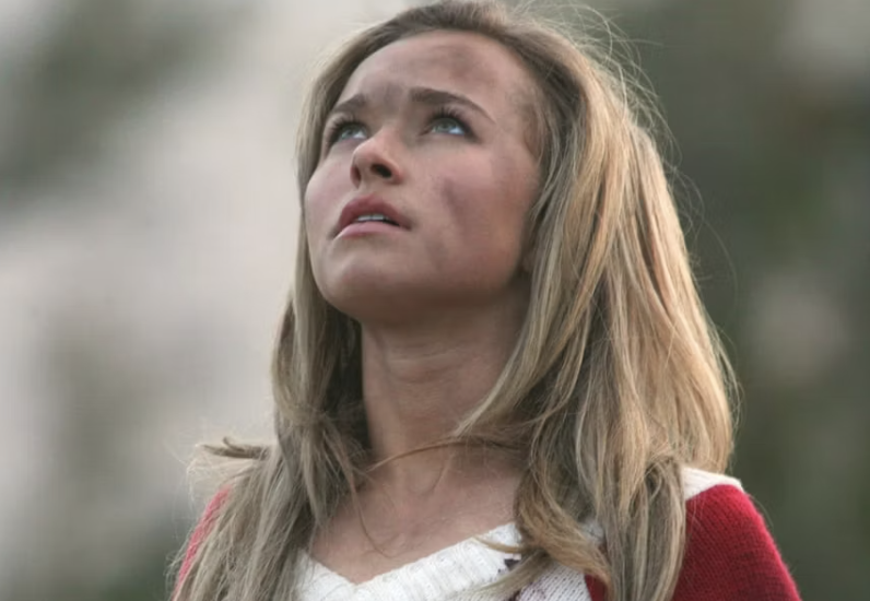 Hayden Panettiere looks up thoughtfully with a smudged face, wearing a white knit top under a red jacket