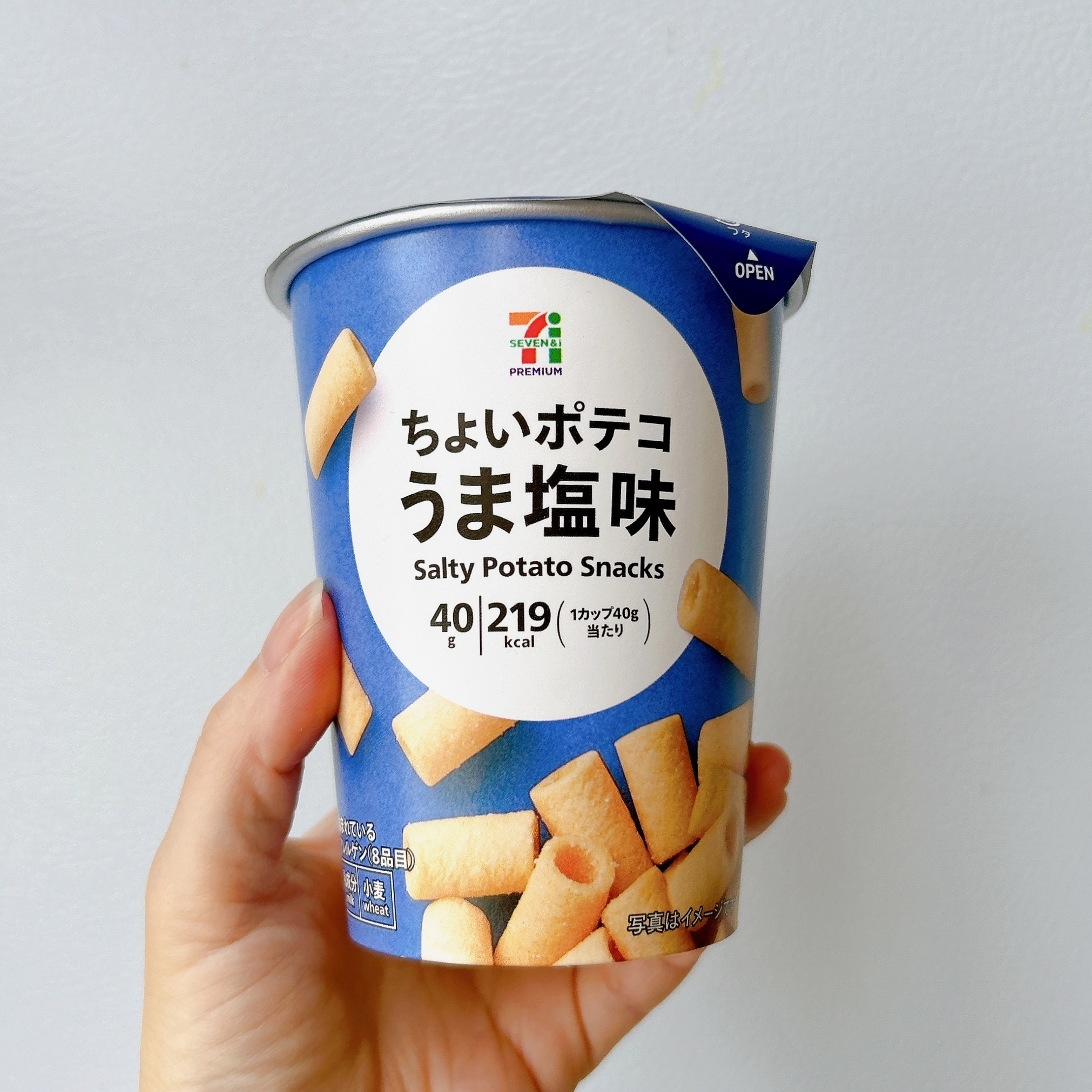 手に持った7プレミアムのうま塩味ポテトスナックのカップ。カロリーは219kcalと表示。