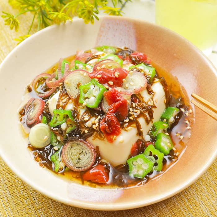 お皿に盛り付けられた豆腐の上に、刻んだ野菜とたれがかかっている。