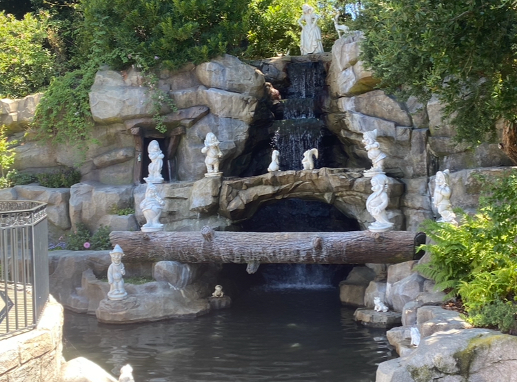 A garden waterfall scene featuring statues of the Seven Dwarfs from Snow White placed around the cascading water