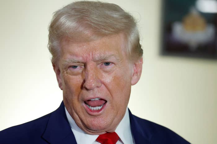 Donald Trump, wearing a suit and tie, speaking with his mouth open