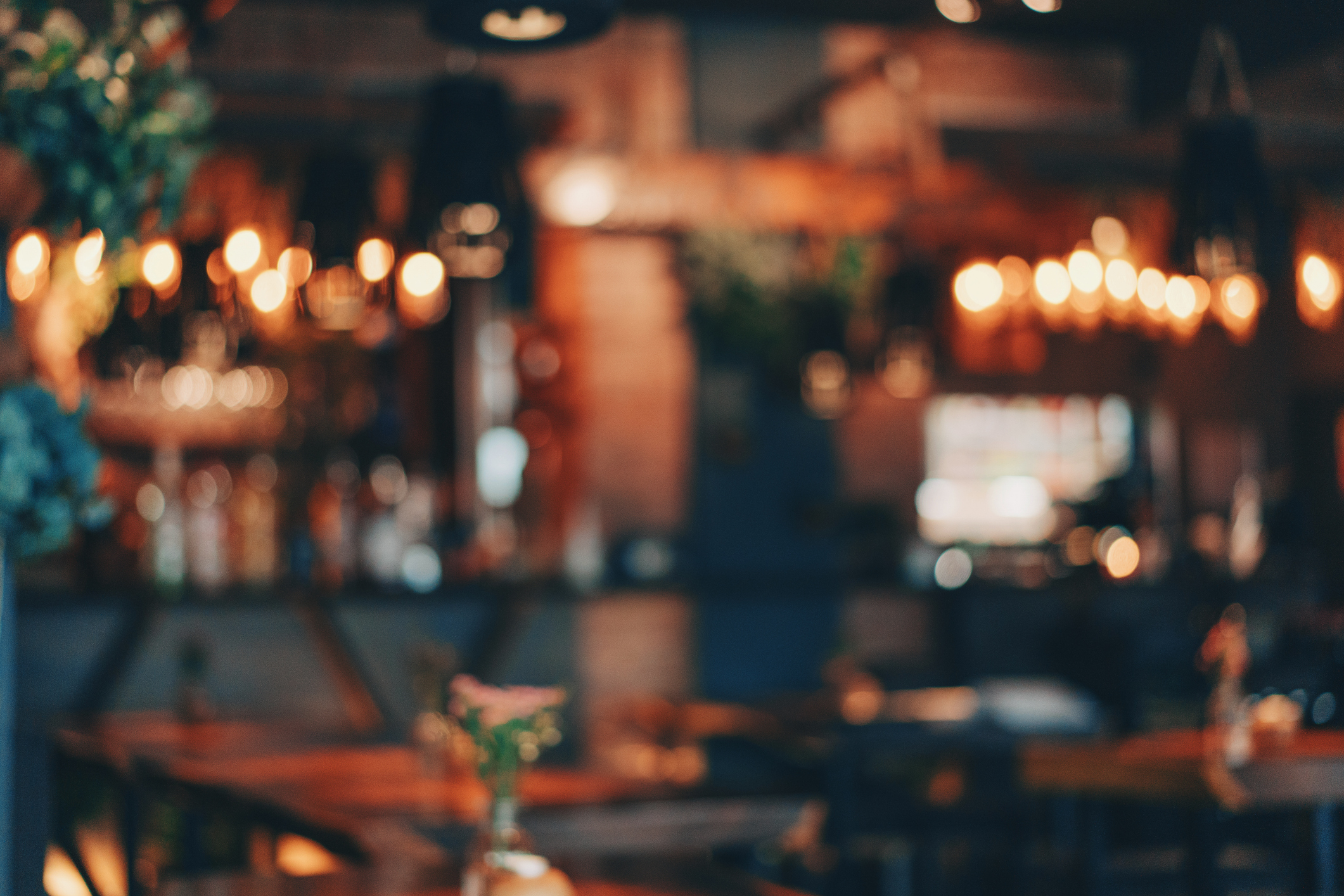 A dimly lit, romantic restaurant setting with hanging lights and blurred tables, creating an intimate atmosphere for dining