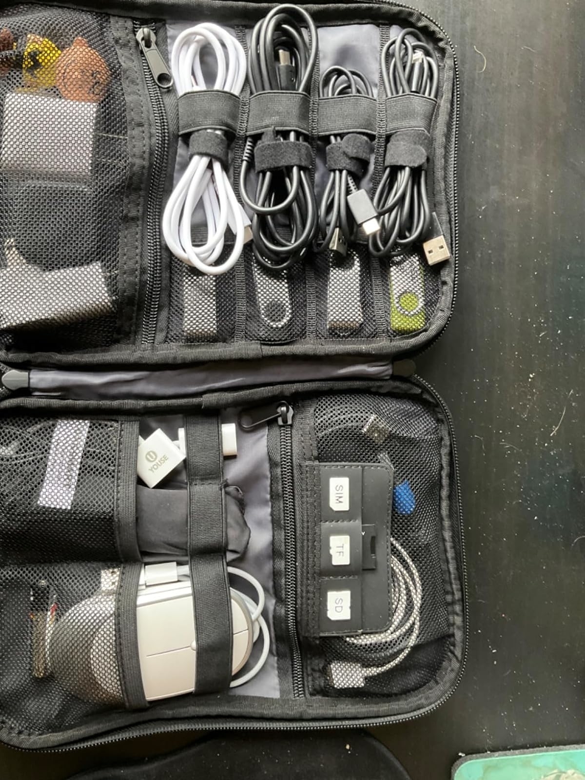 A reviewer&#x27;s organized travel tech bag with various neatly arranged cables, adapters, and a computer mouse in mesh pockets, ideal for tech-savvy travelers