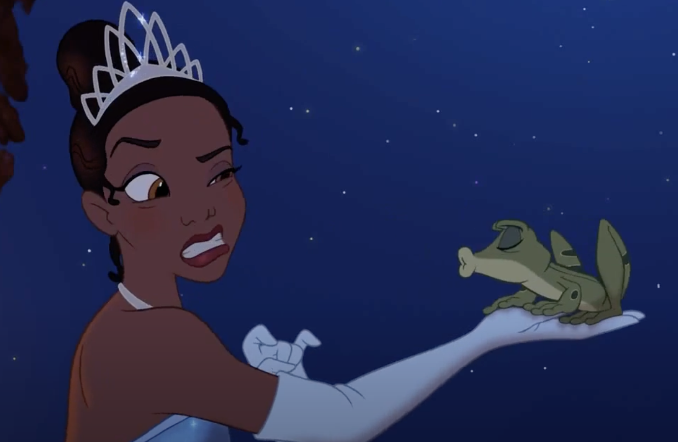 Tiana, wearing a white gown and tiara, holds a puckering frog on her gloved hand, looking displeased, from Disney's The Princess and the Frog