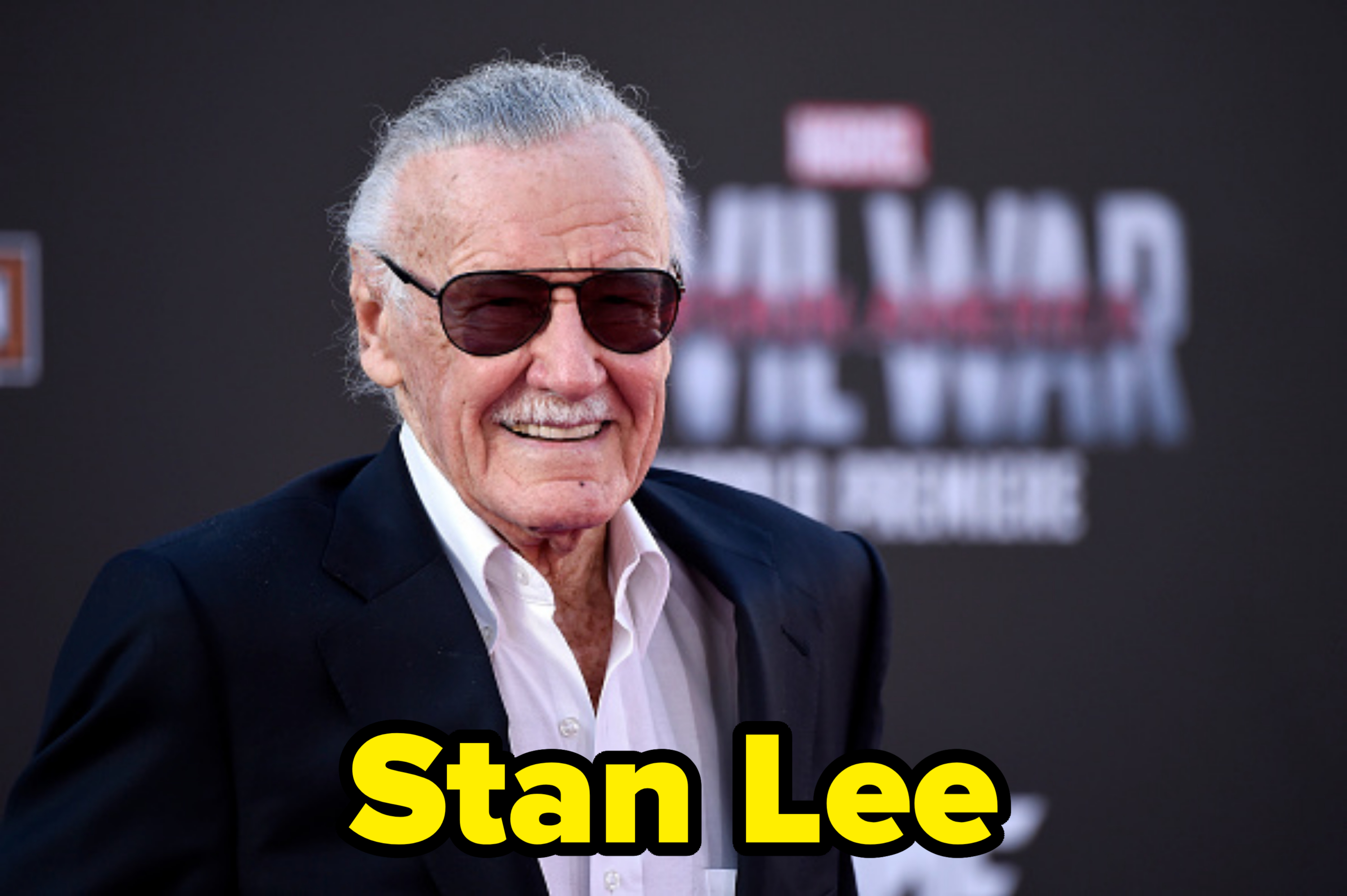 Stan Lee, smiling, wearing sunglasses, a white shirt, and a dark blazer at the premiere of "Captain America: Civil War."