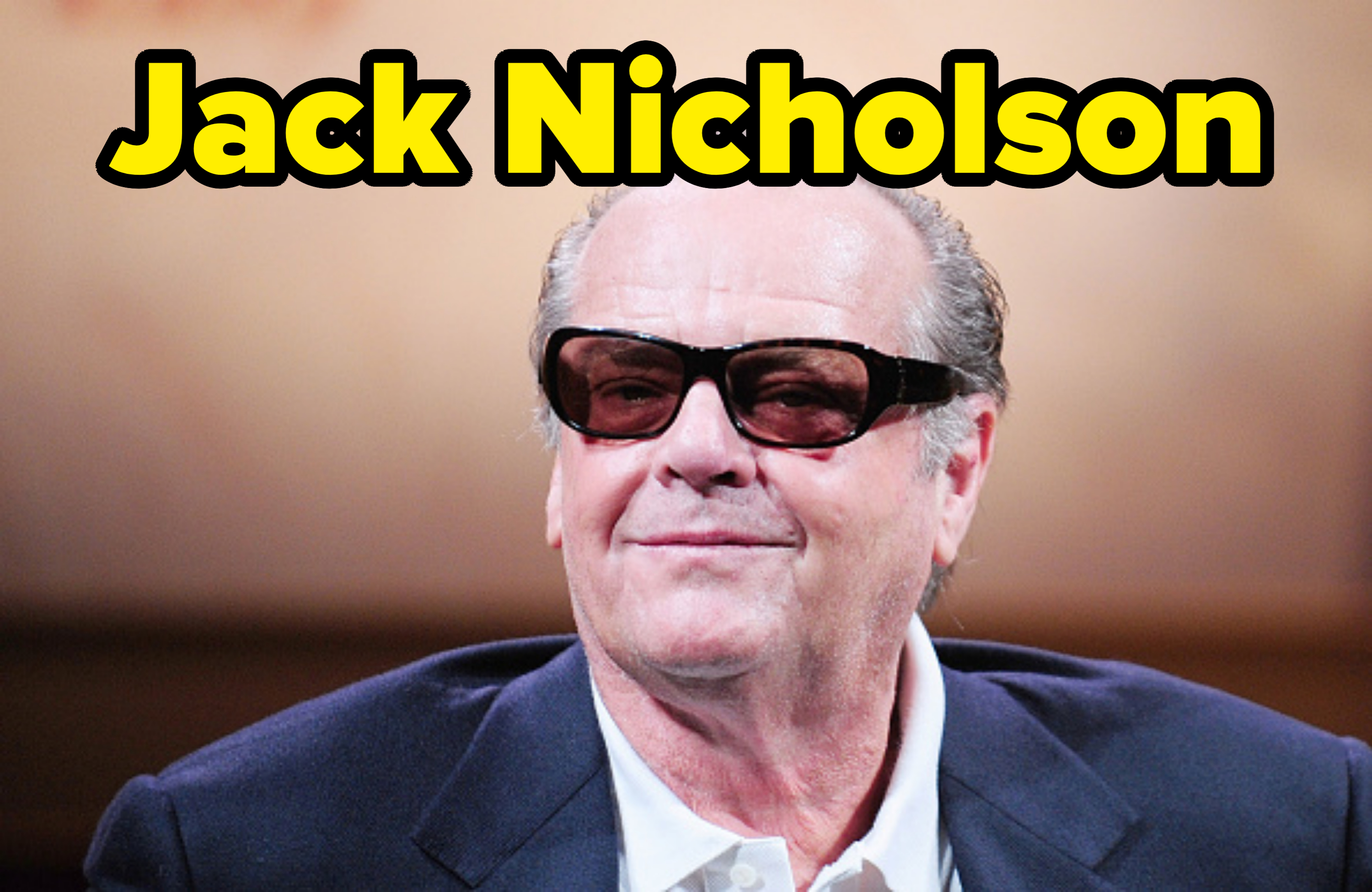 Jack Nicholson wearing dark sunglasses and a blazer, smiling at an event