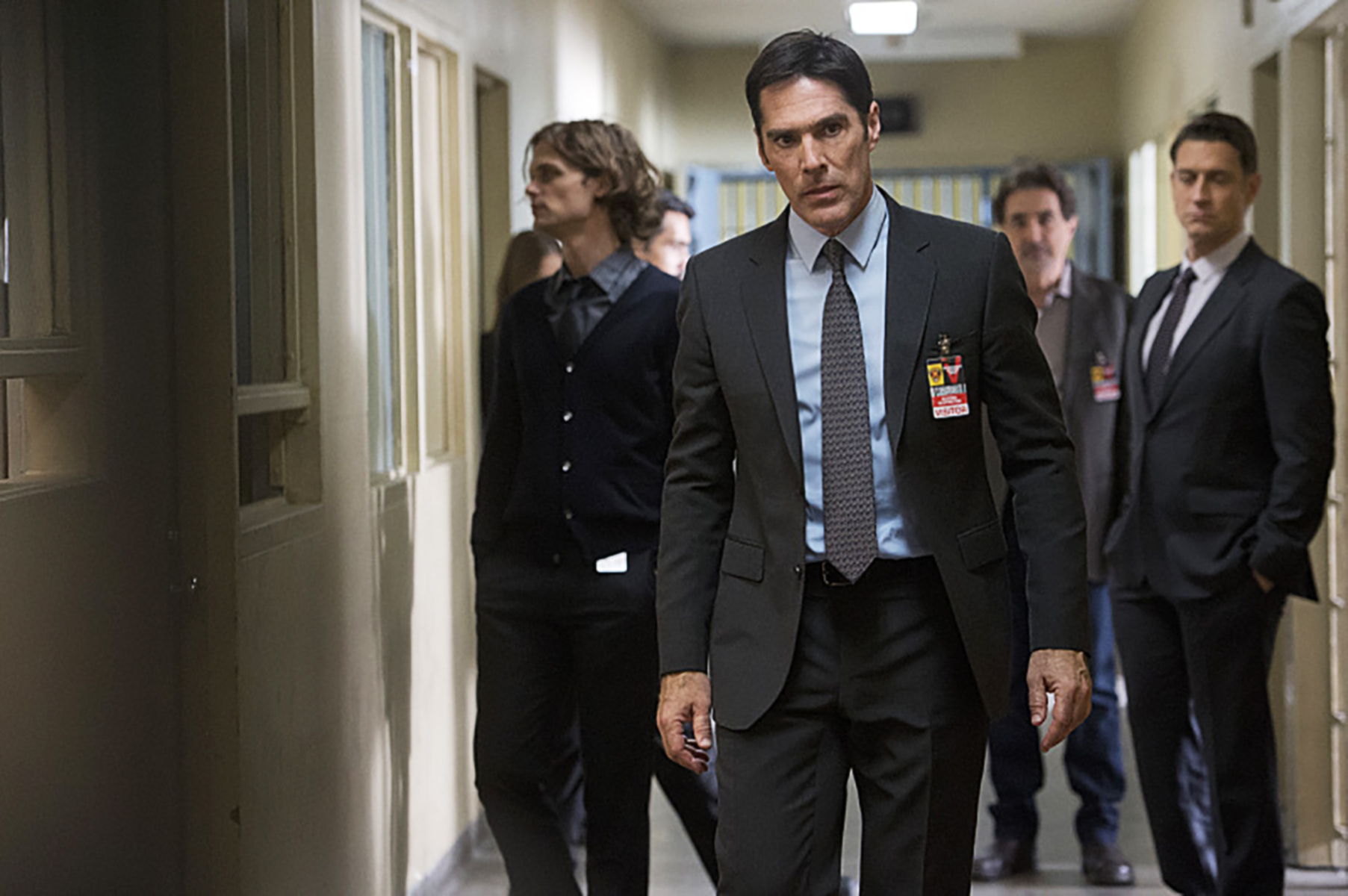 Matthew Gray Gubler, Thomas Gibson, Shemar Moore, Joe Mantegna, and AJ Cook in a corridor wearing FBI badges and professional attire