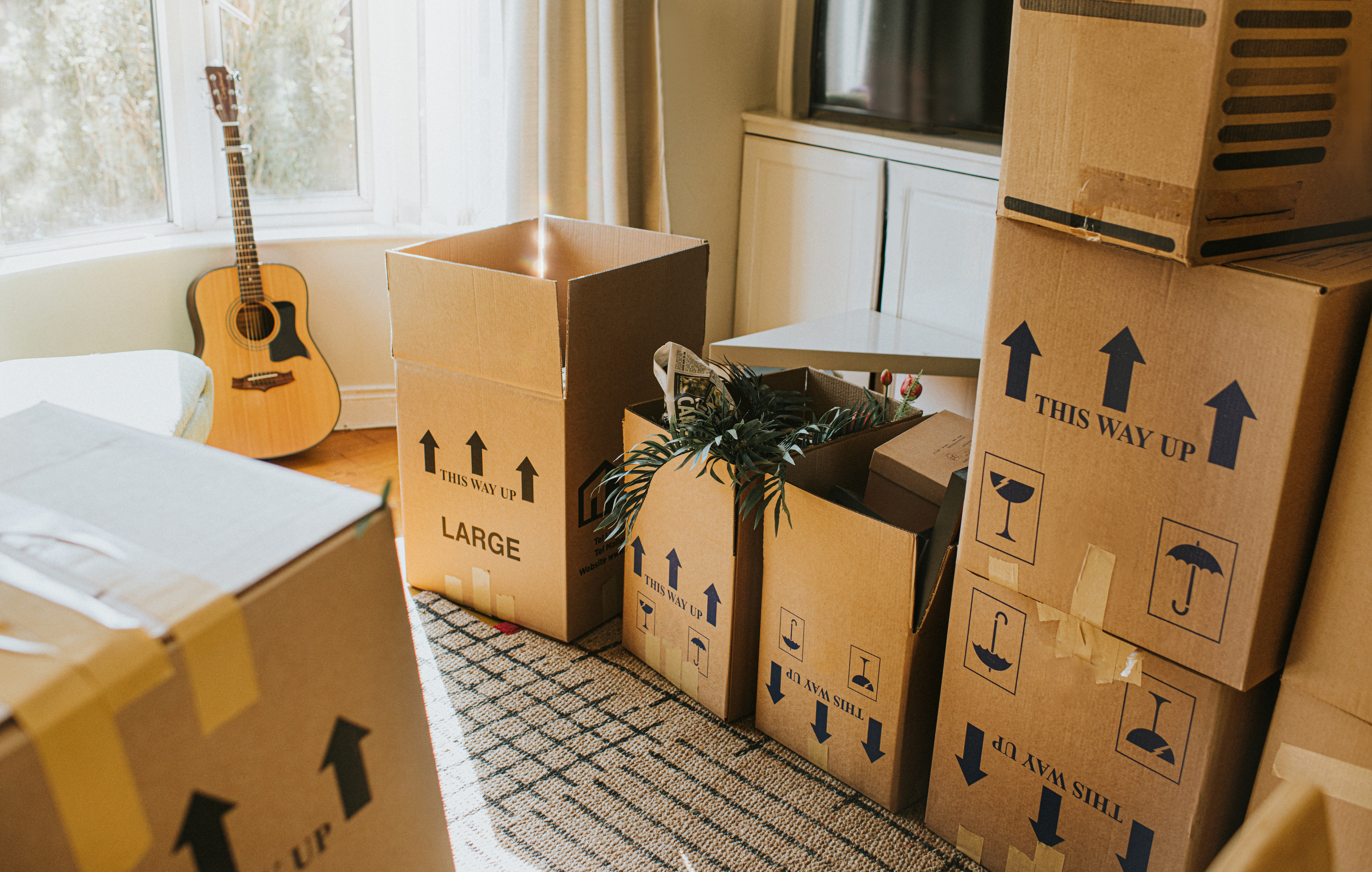 Stacked moving boxes and a guitar in a living room