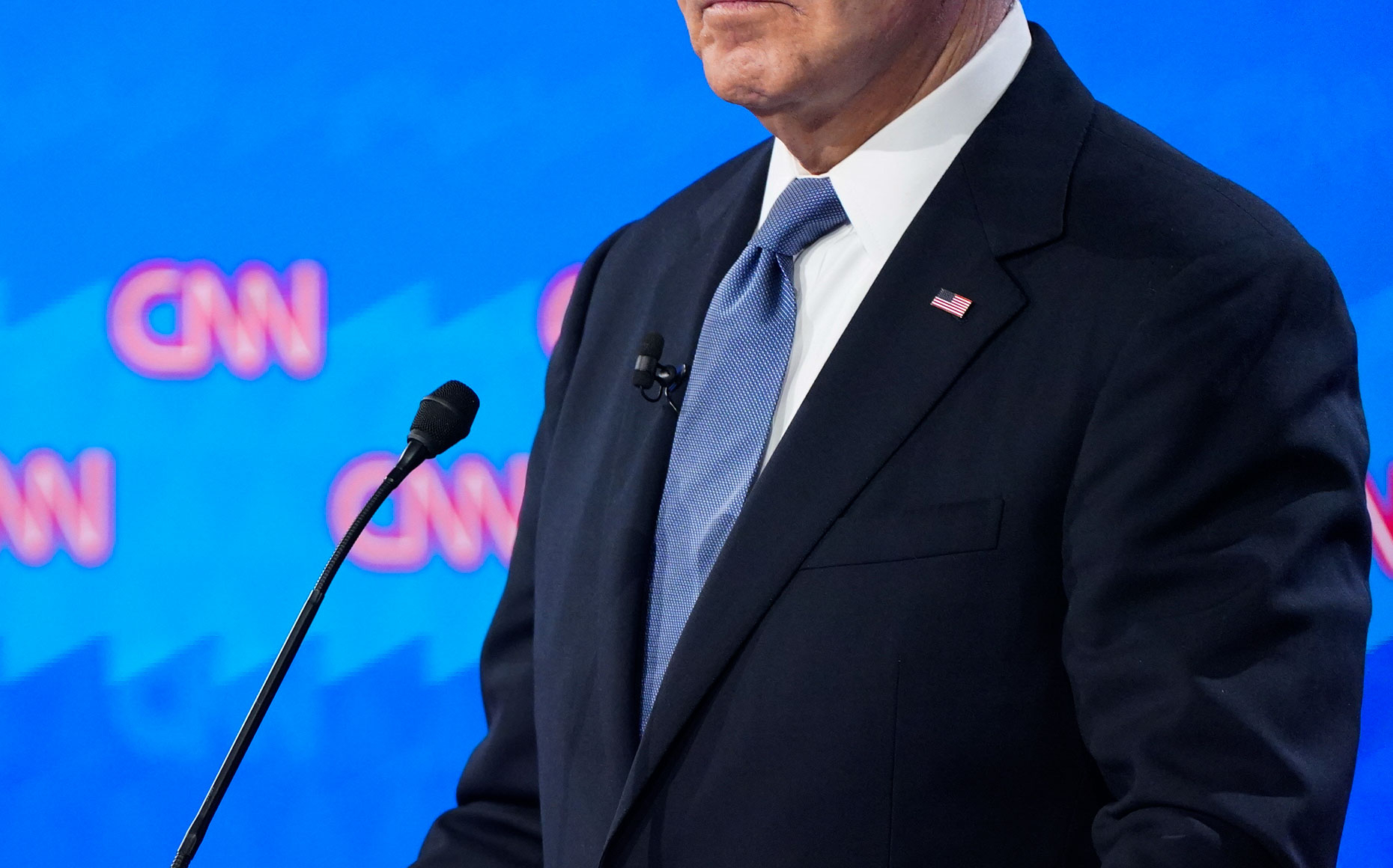 A man in a suit and tie stands at a podium with a CNN backdrop