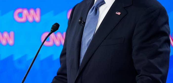 A man in a suit and tie stands at a podium with a CNN backdrop