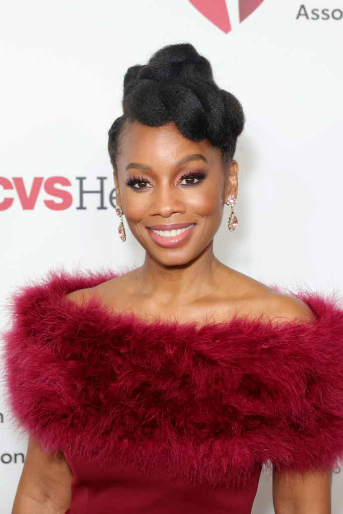 Anika Noni Rose smiles on the red carpet in a glamorous off-shoulder dress with a fur-like neckline
