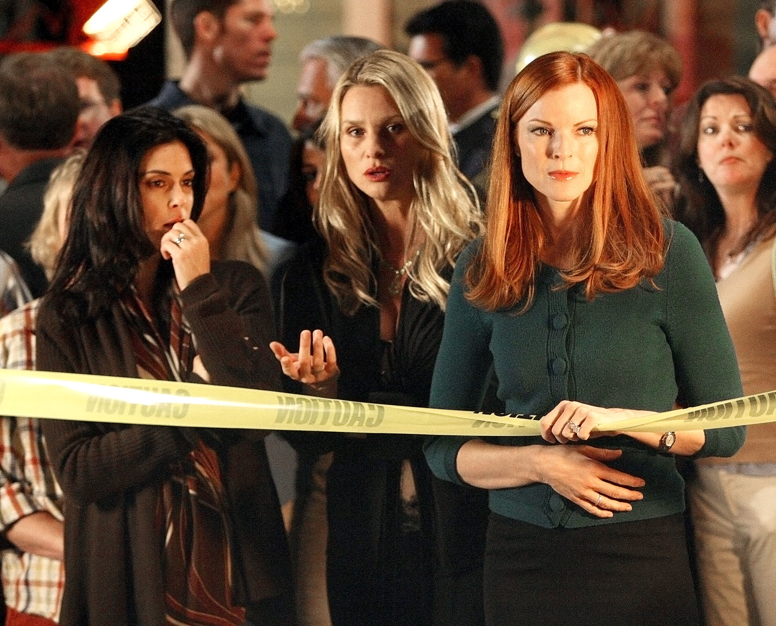 Teri Hatcher, Nicollette Sheridan, and Marcia Cross standing behind a caution tape, in a scene from "Desperate Housewives"