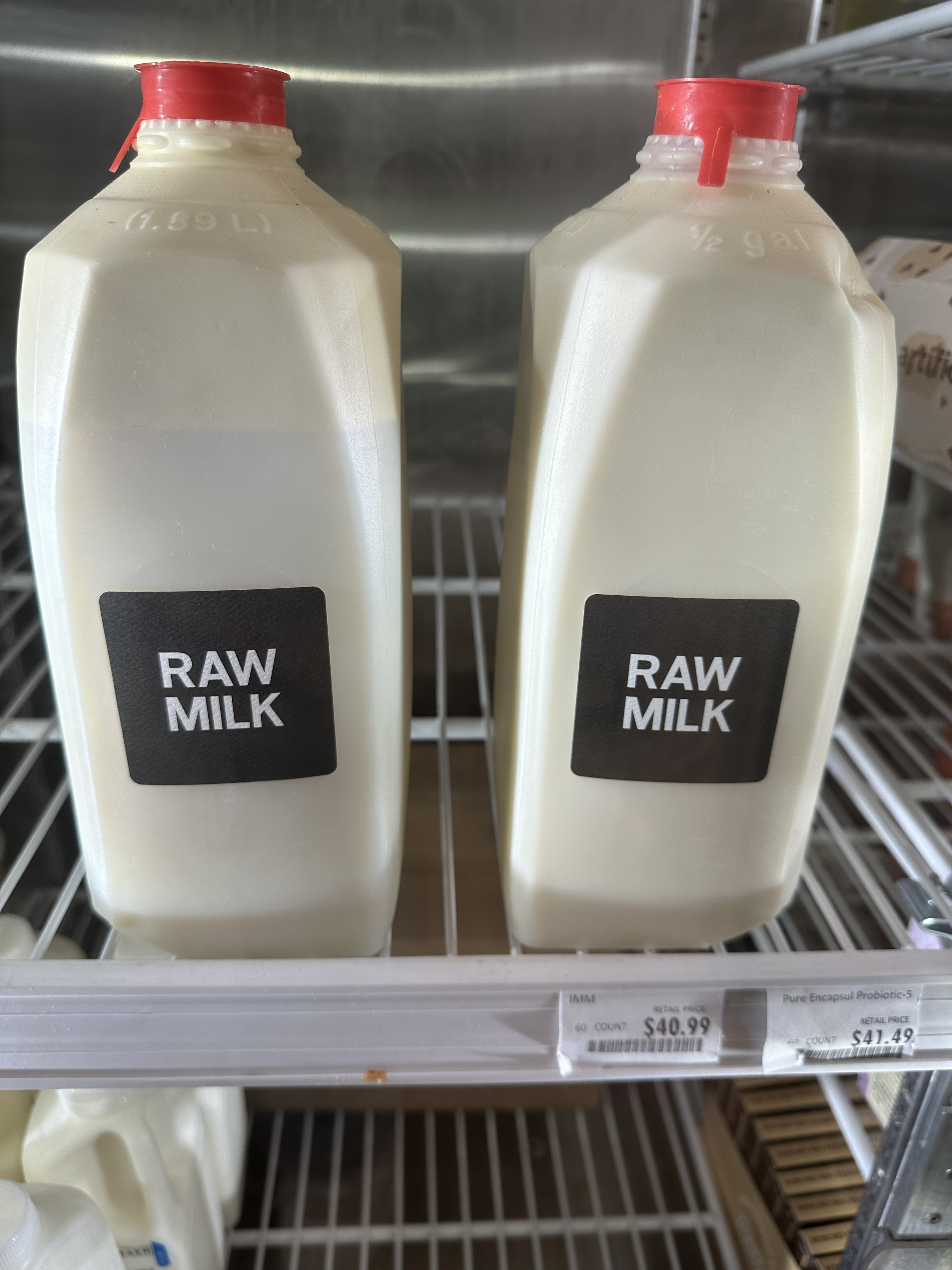 Two bottles labeled "RAW MILK" on a shelf in a store. The price tag reads $40.99 per gallon