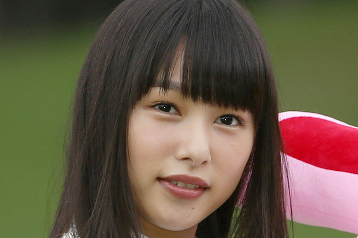 女性が白い服を着て、大きなピンクのぬいぐるみを抱えて微笑んでいる。