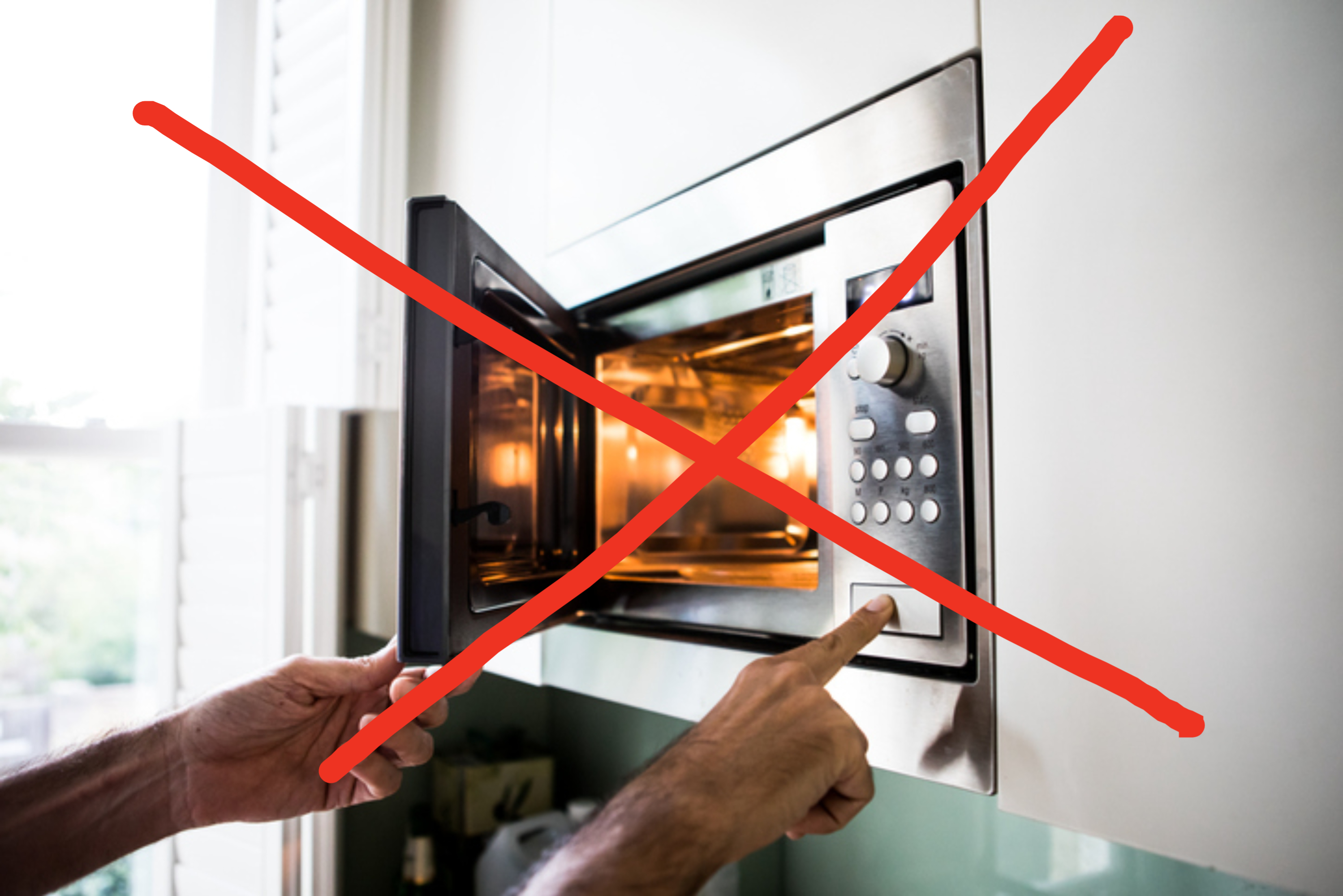 A person is pressing a button on a microwave oven with its door open. The microwave appears to be in a modern kitchen setting
