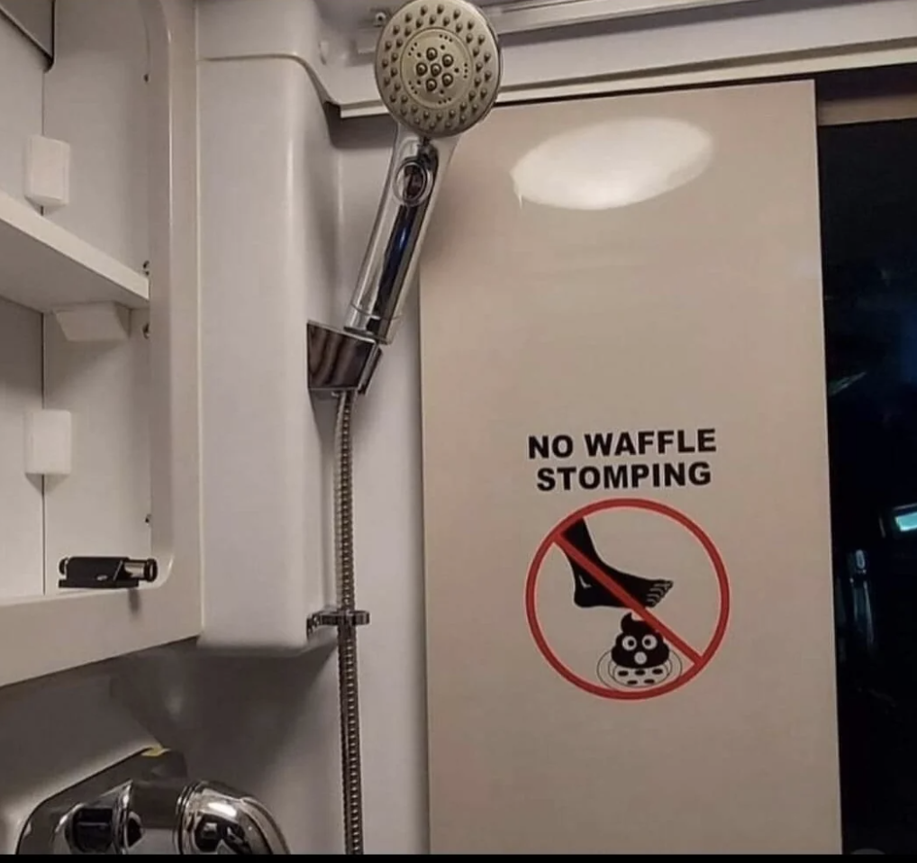 Shower area with a sign on the door stating "No Waffle Stomping" under a graphic depicting a foot and drain in a prohibition symbol