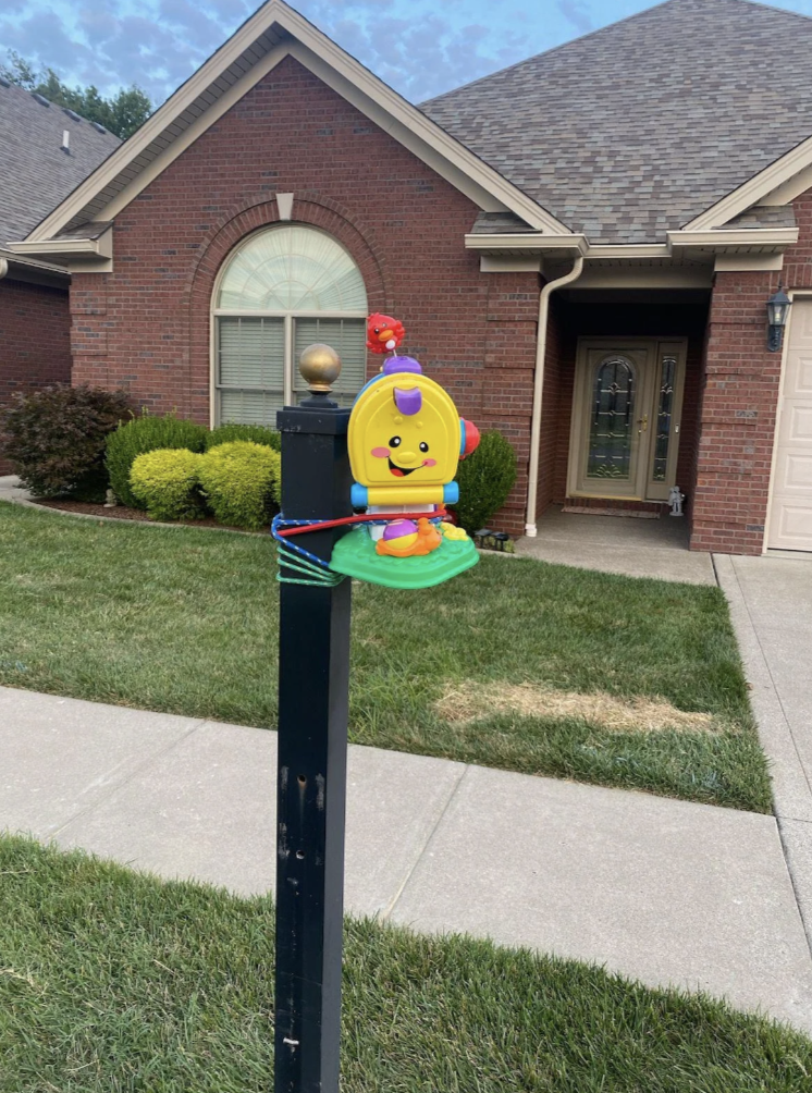 Toy caterpillar attached to a mailbox stand in front of a suburban brick house