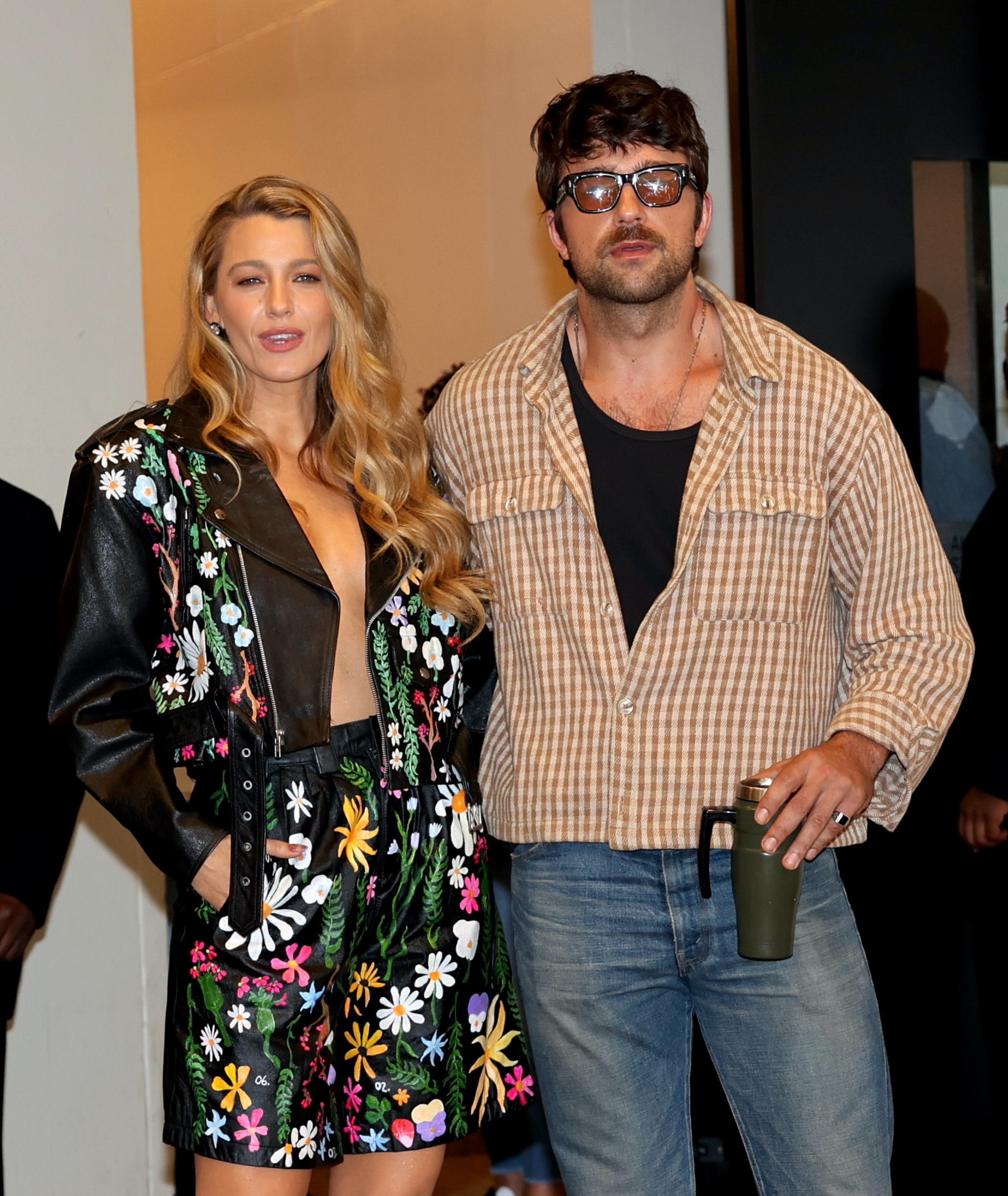 Blake Lively in a floral outfit and Brandon Sklenar in a plaid shirt posing together indoors