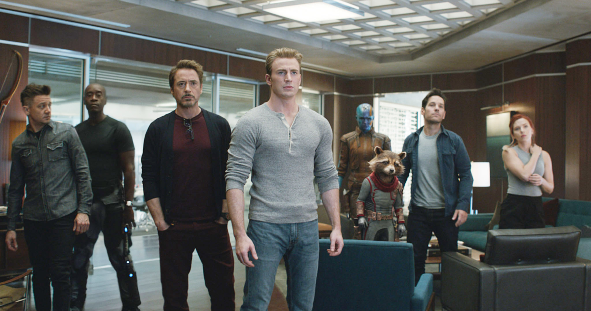 Jeremy Renner, Don Cheadle, Robert Downey Jr., Chris Evans, Karen Gillan, Rocket Raccoon (animated), Paul Rudd, and Scarlett Johansson stand in a room