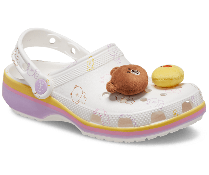 White Crocs shoe with a playful bear and chick plush attached on top and a pattern of bear and chick illustrations