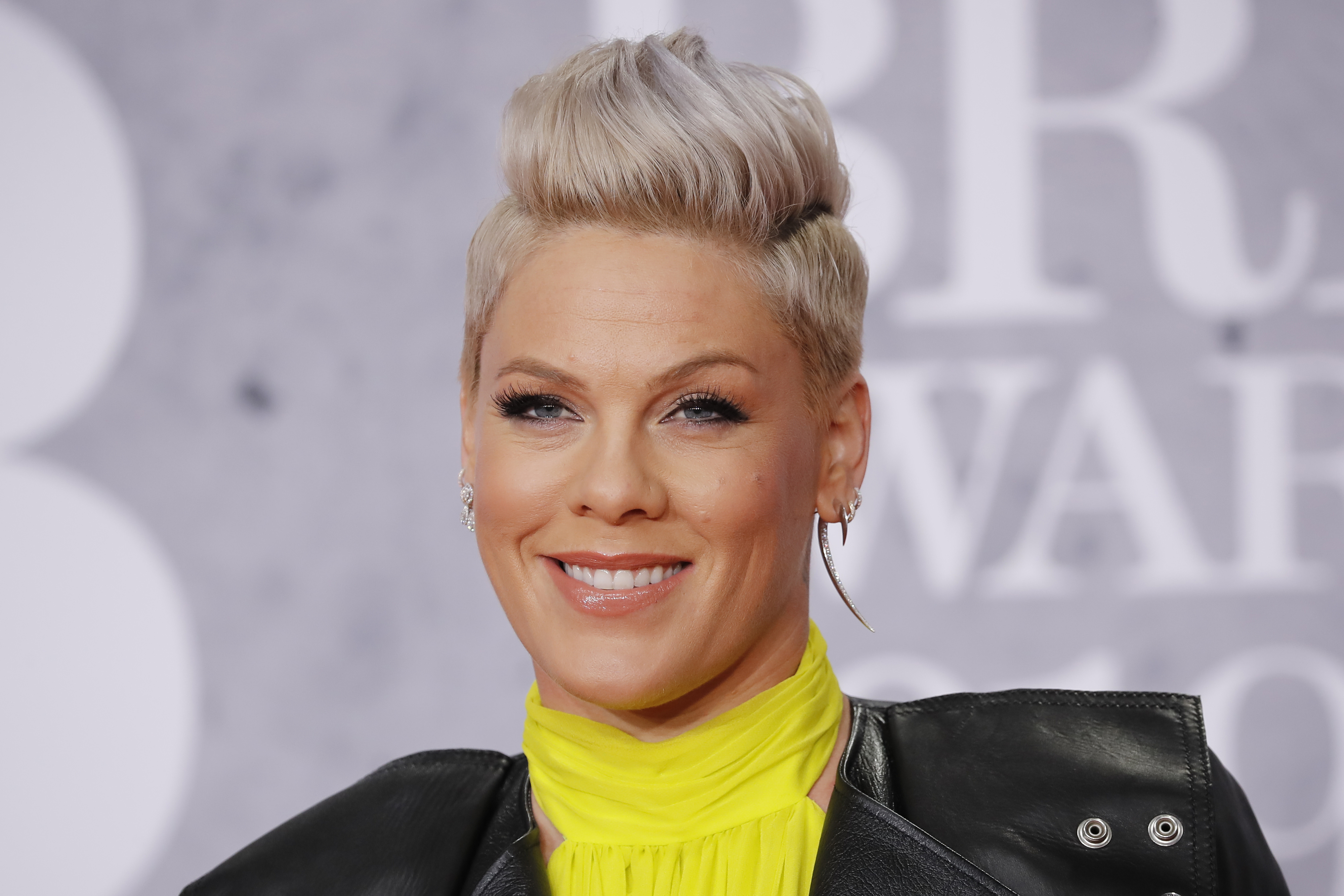 Pink smiles on the red carpet wearing a bright high-neck dress and a leather jacket at the BRIT Awards 2019