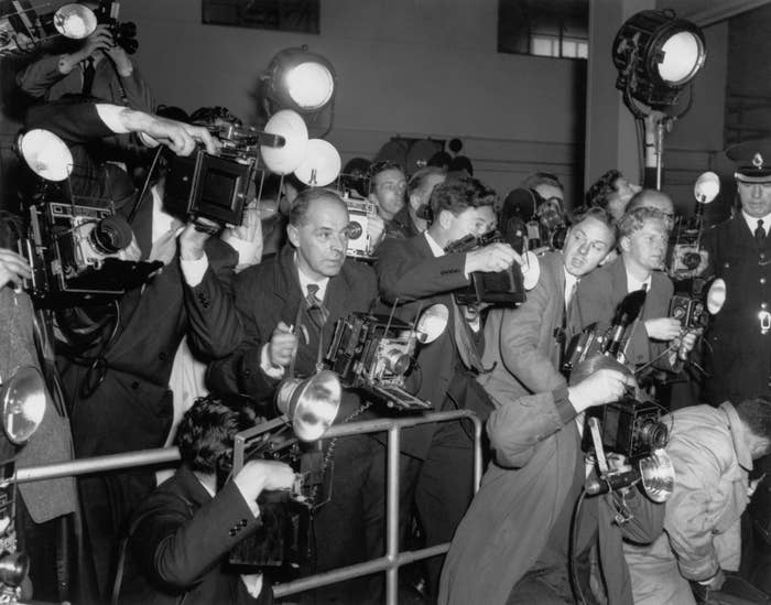 A group of photographers and journalists crowding, holding cameras and equipment, capturing a moment