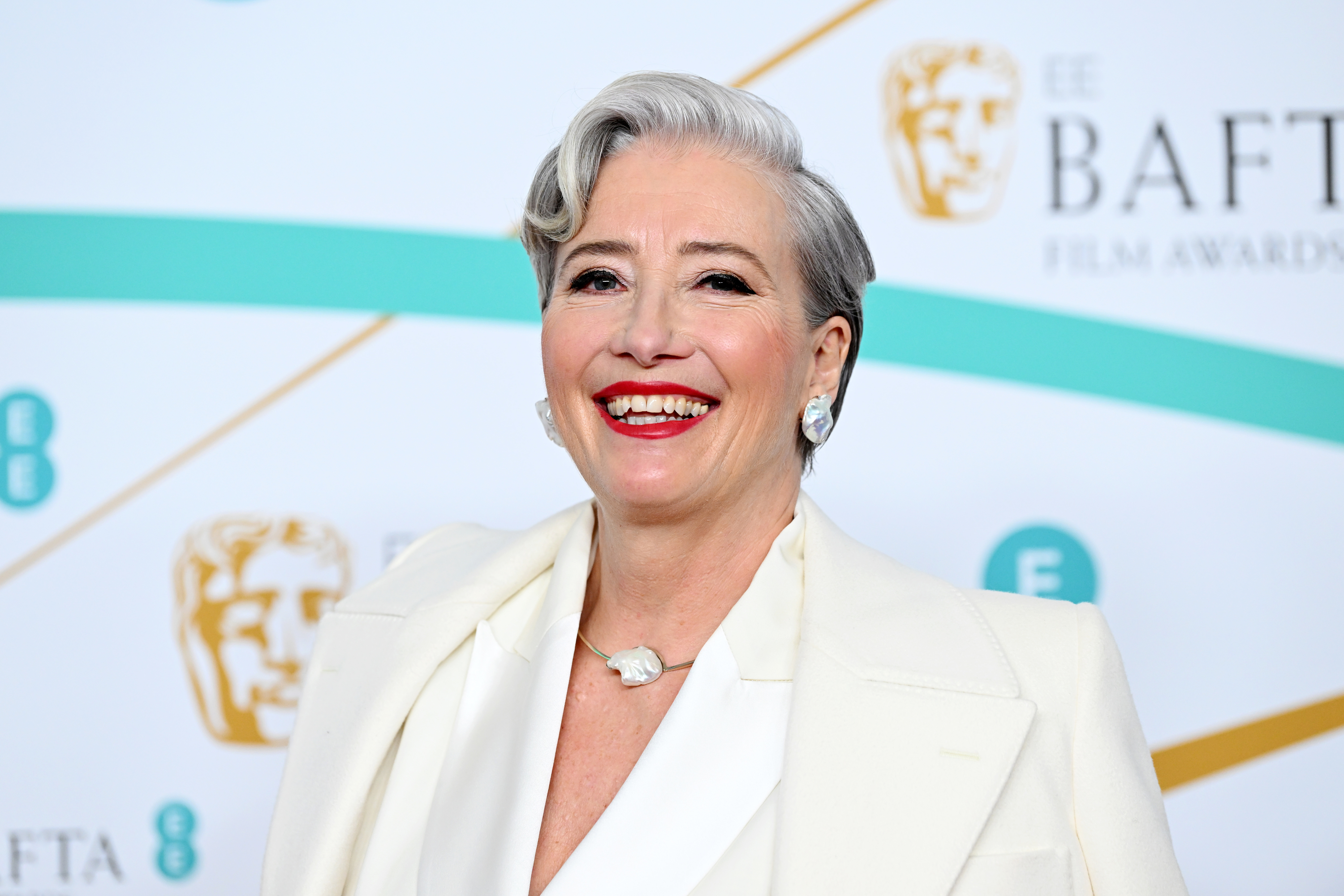 Emma Thompson at the BAFTA Film Awards, wearing an elegant white suit and smiling widely