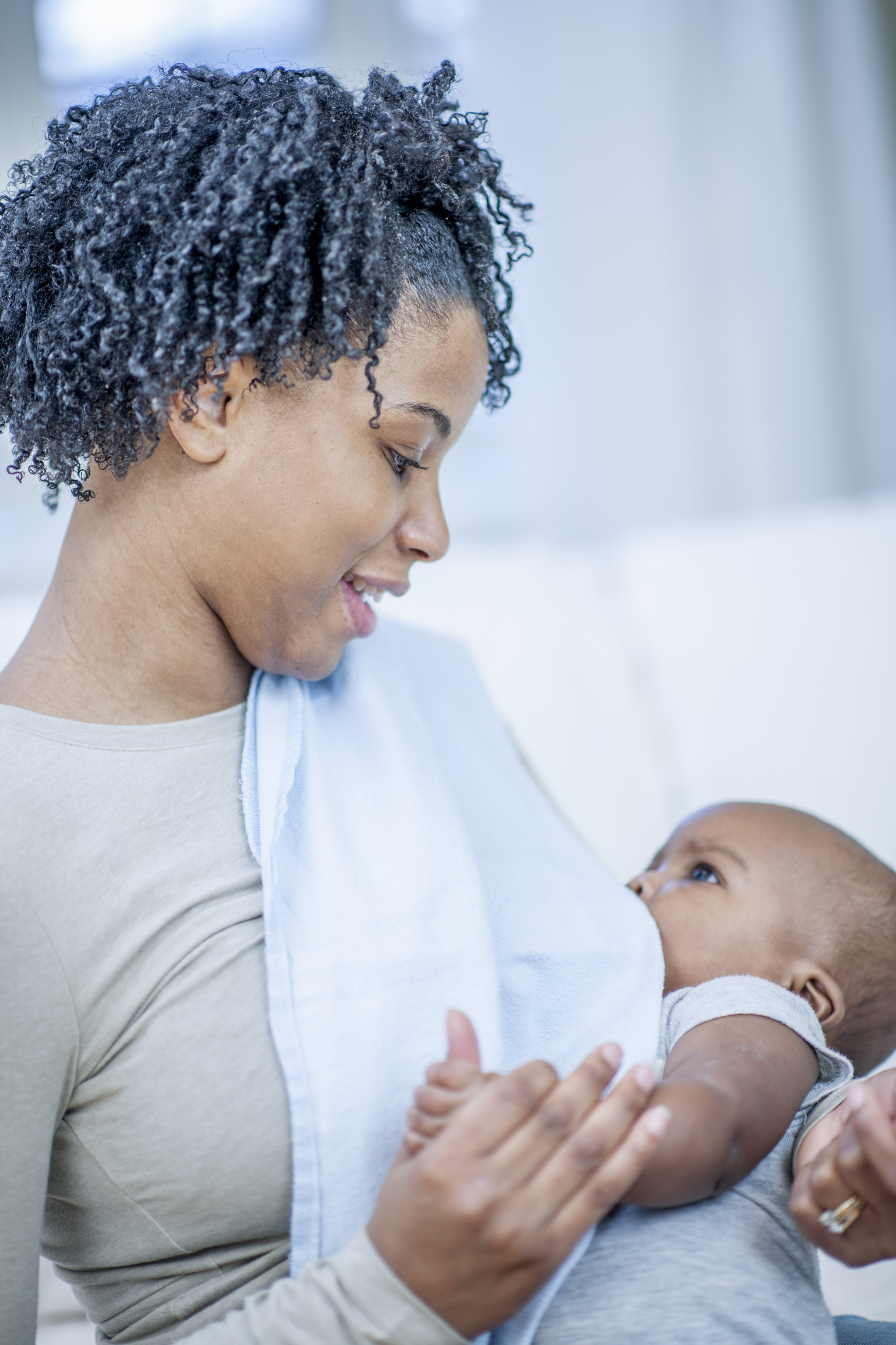 A smiling woman is breastfeeding a baby