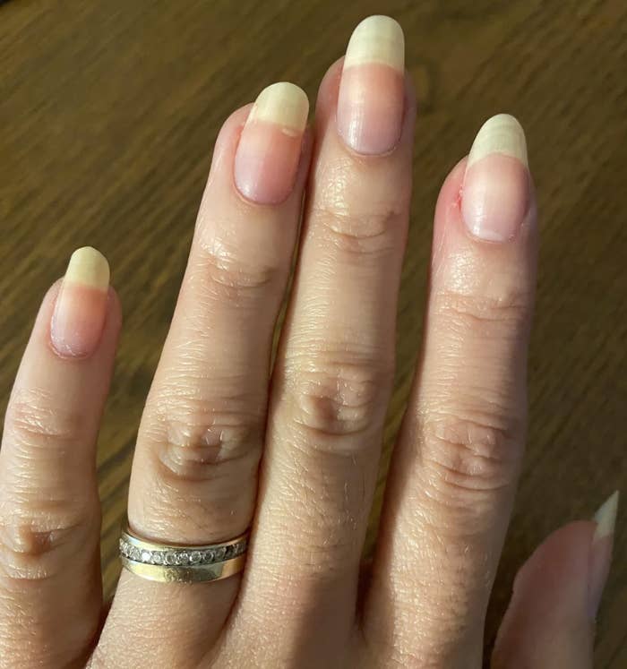 A hand showing long, well-maintained nails with two rings on the ring finger. The Reddit post is titled: "Longest my nails have been. Can't decide to keep it at this length or shorten them."