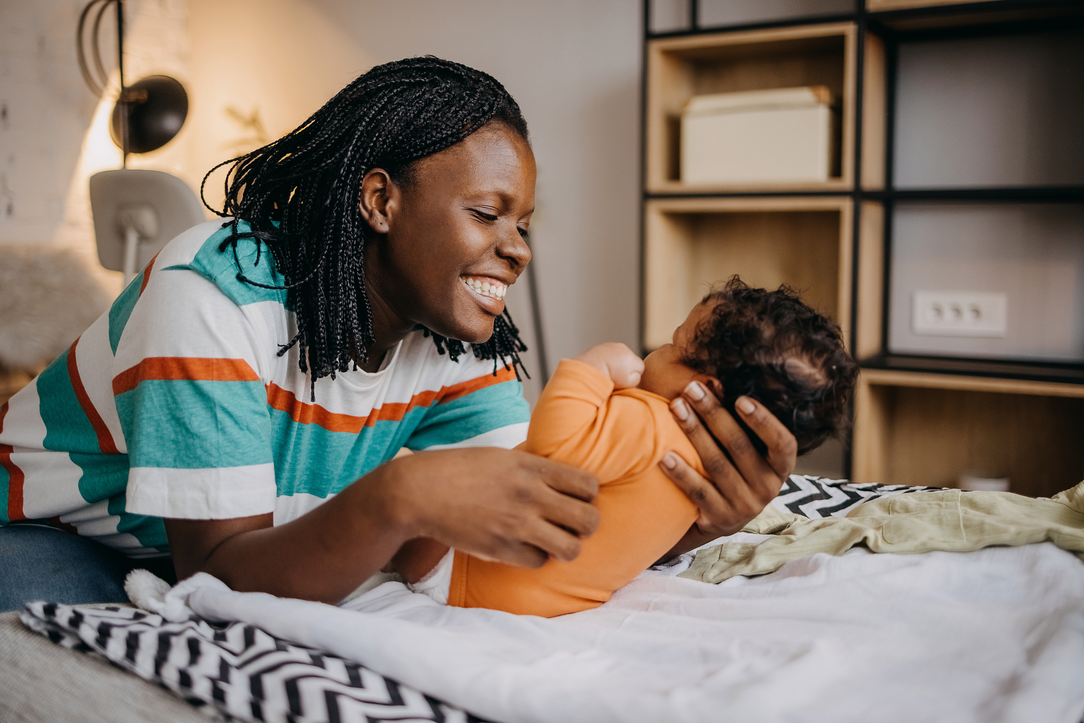 Mother smiling and holding her baby in a cozy room