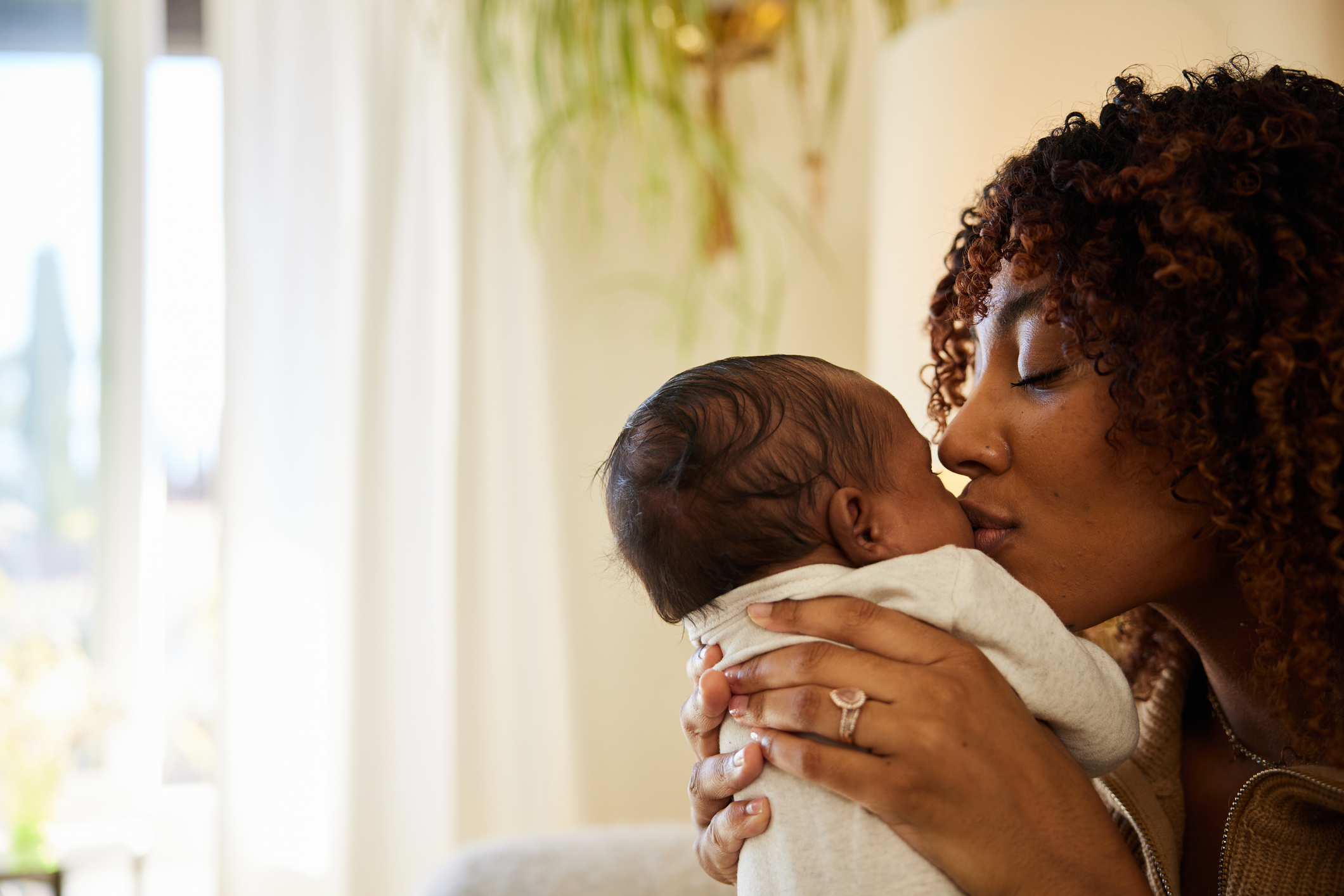 A woman holds and kisses a baby, conveying a moment of tender affection between the two