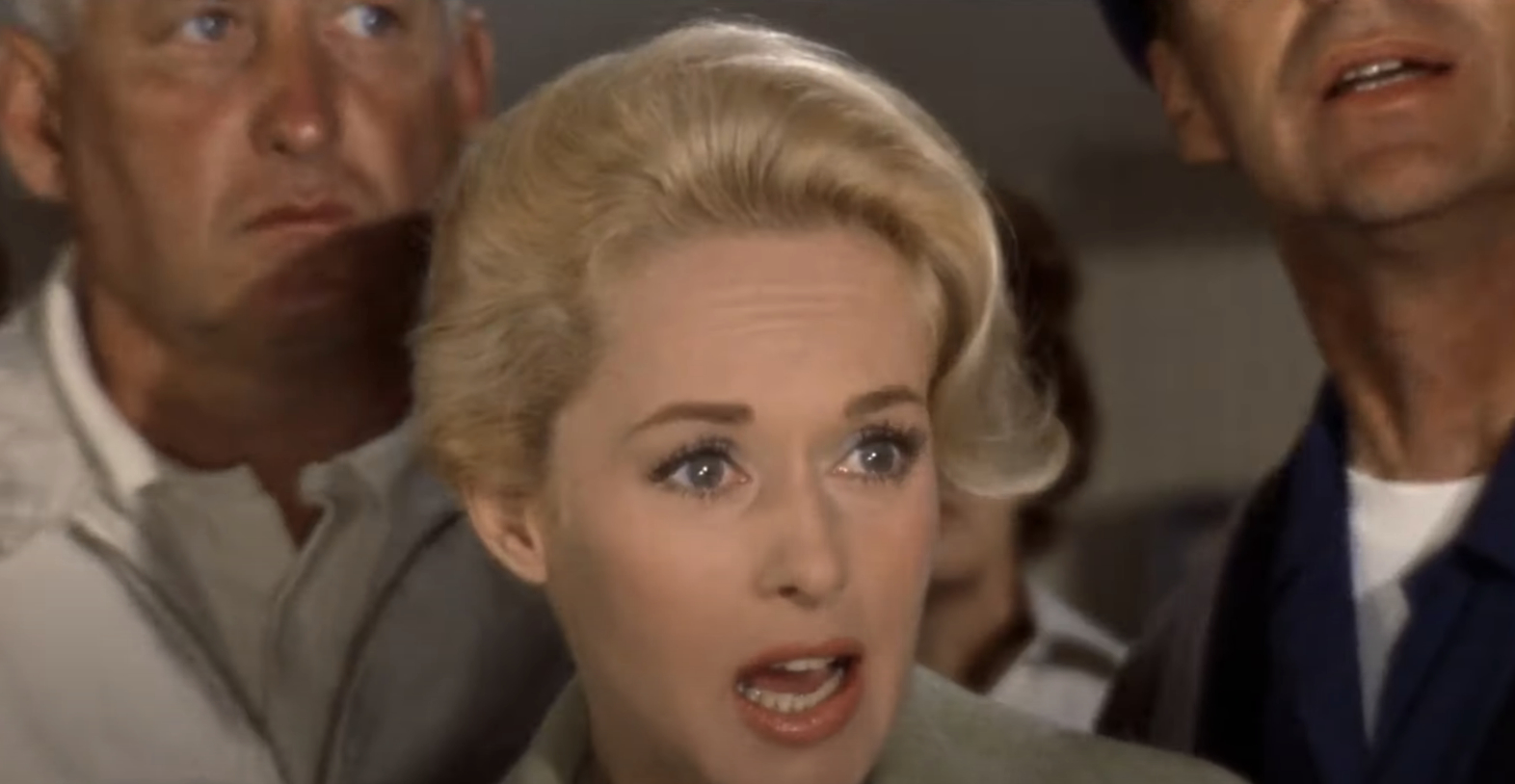 Tippi Hedren as Melanie Daniels appears alarmed in a scene from the movie &quot;The Birds,&quot; with two men in the background, showing expressions of concern