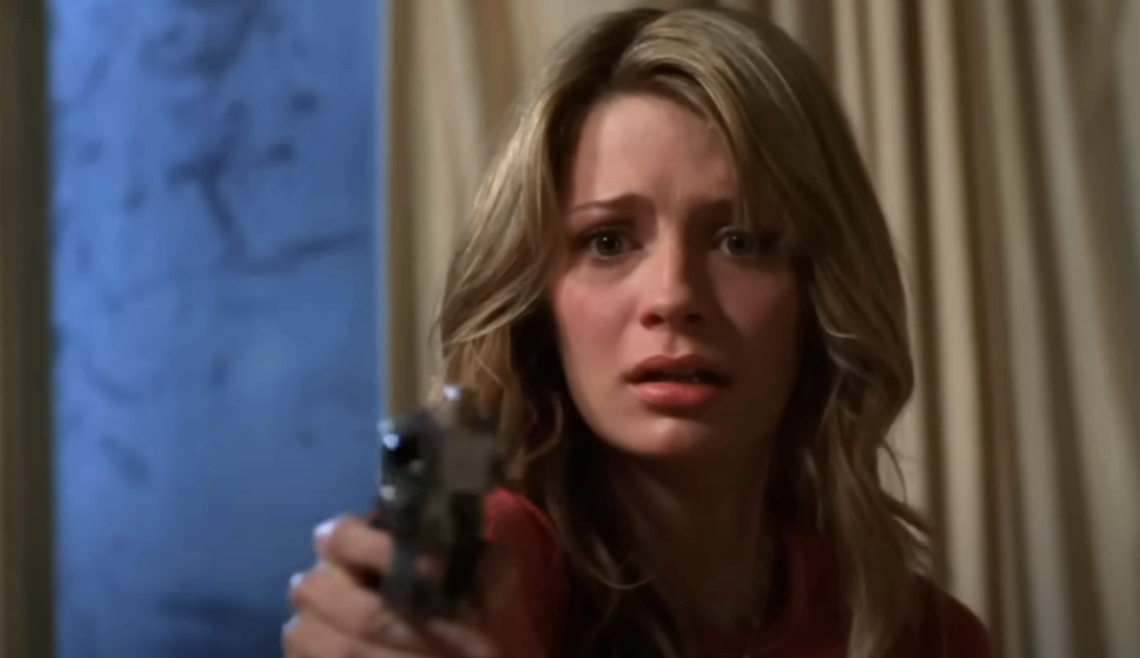 Mischa Barton, in a dramatic scene, points a gun while looking distressed