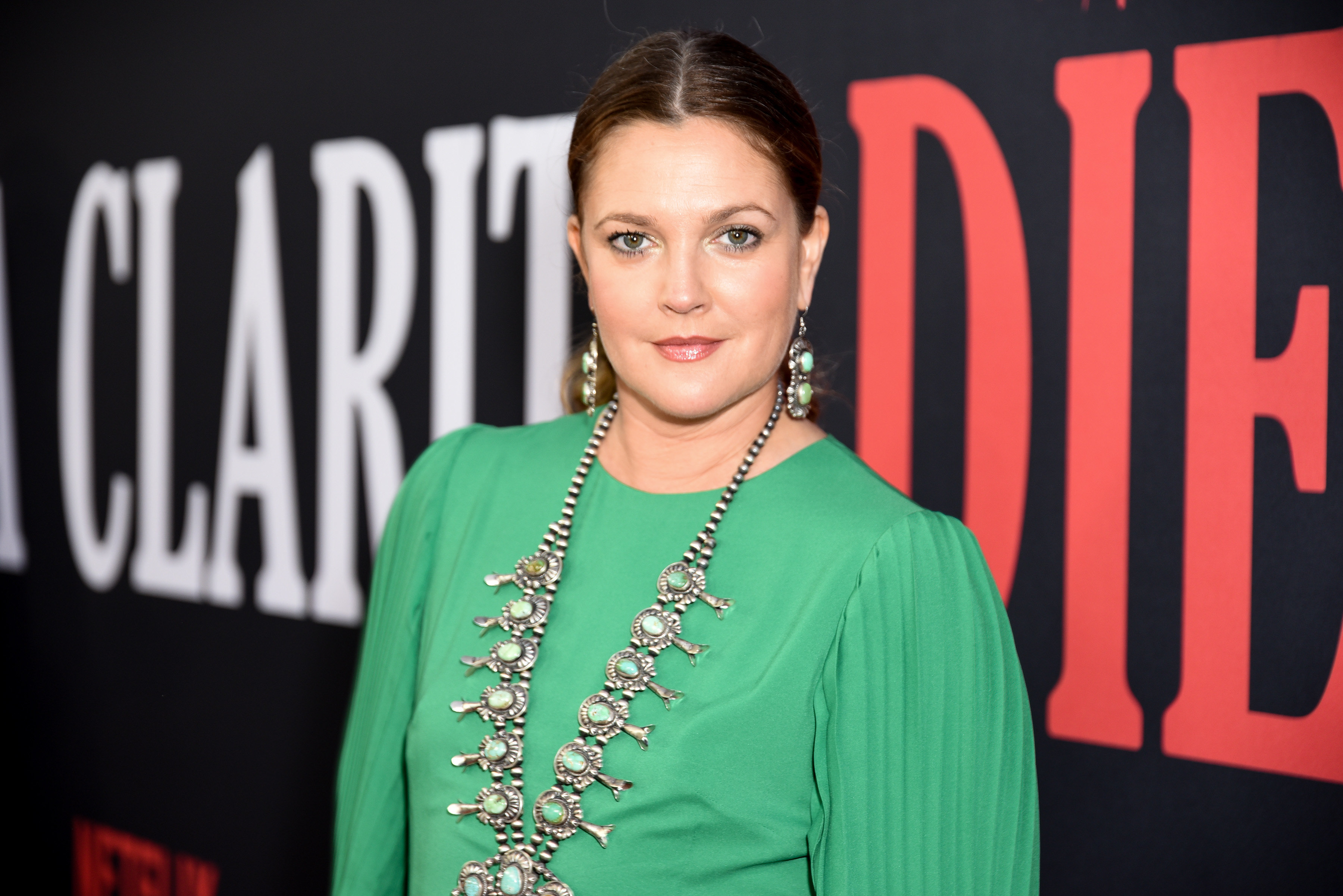 Drew Barrymore at a Santa Clarita Diet event, wearing a green dress and a large statement necklace