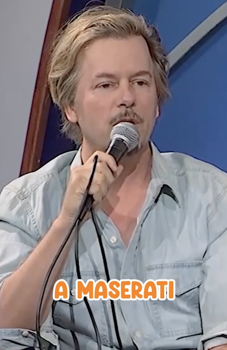 David Spade speaks into a microphone while wearing a casual button-up shirt. Text at the bottom of the image reads &quot;A MASERATI.&quot;
