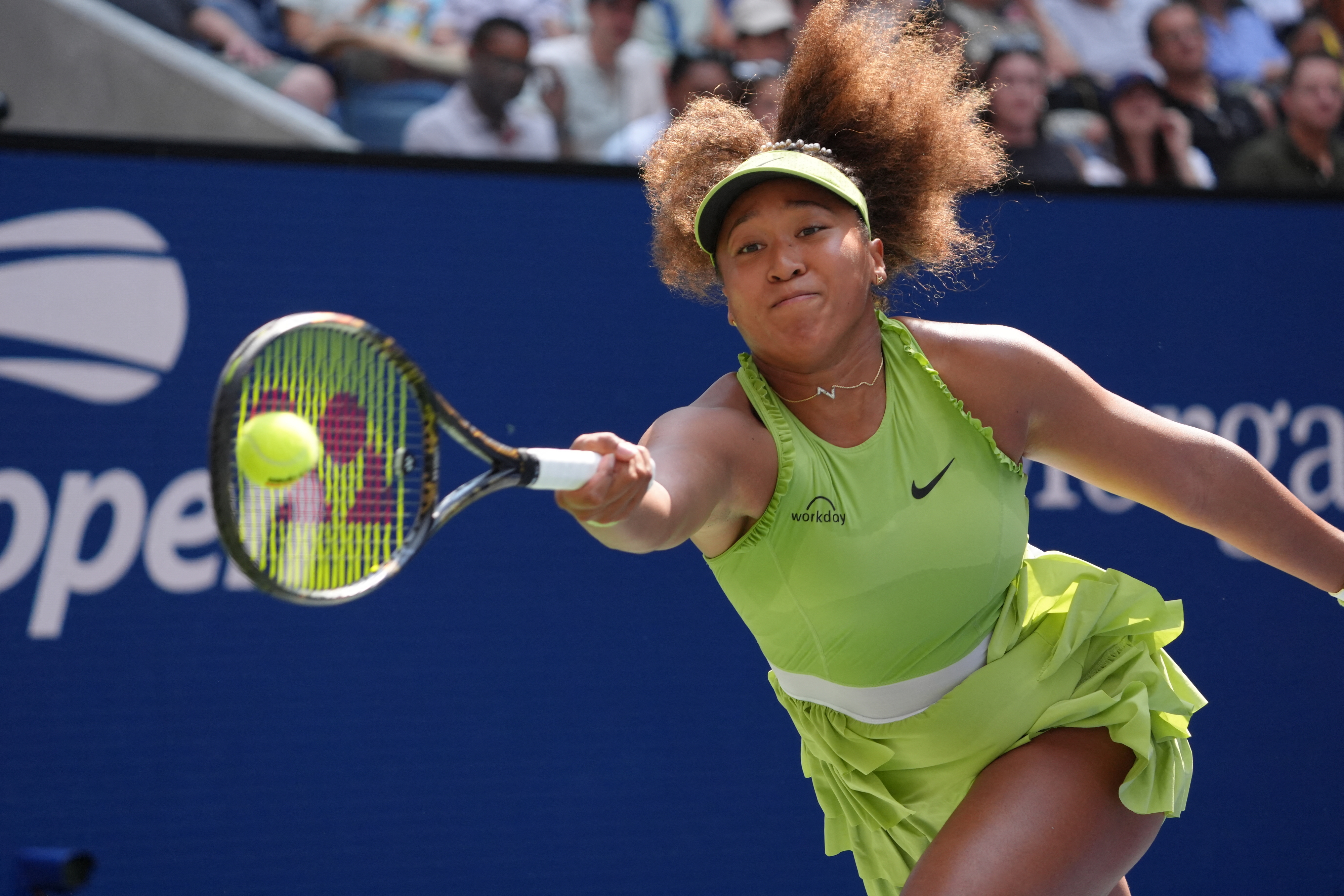 Naomi Osaka, in action, hits a forehand shot during a tennis match, wearing a sleeveless dress and matching visor