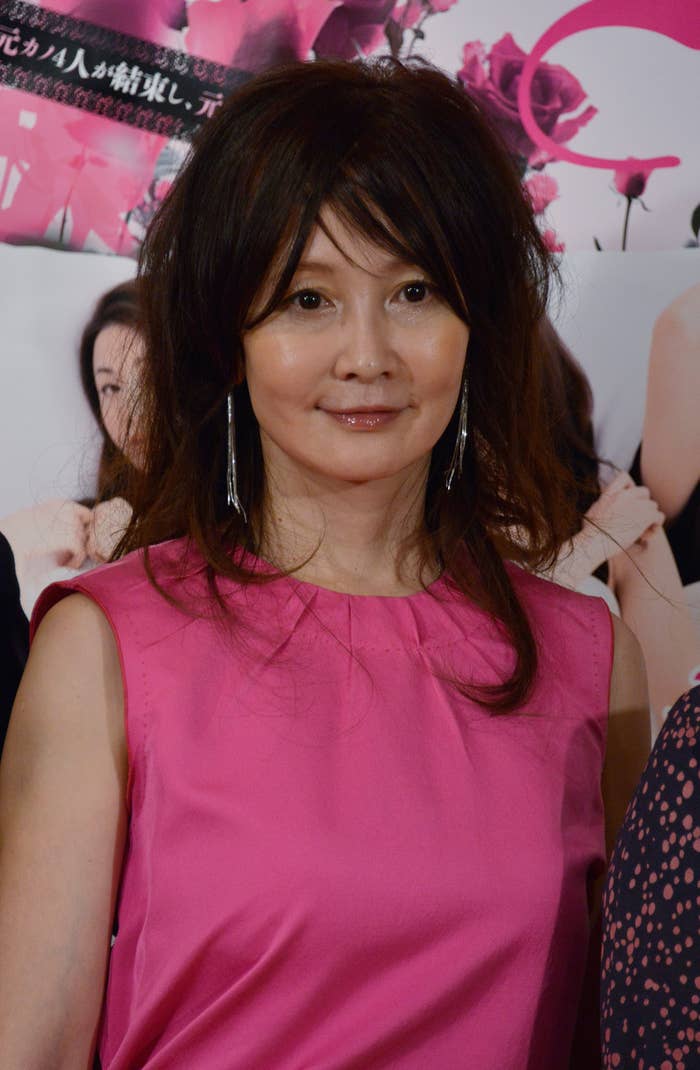 女性がピンクのノースリーブドレスを着て、カメラに向かって微笑んでいる。背景に花や人物のイメージがある。