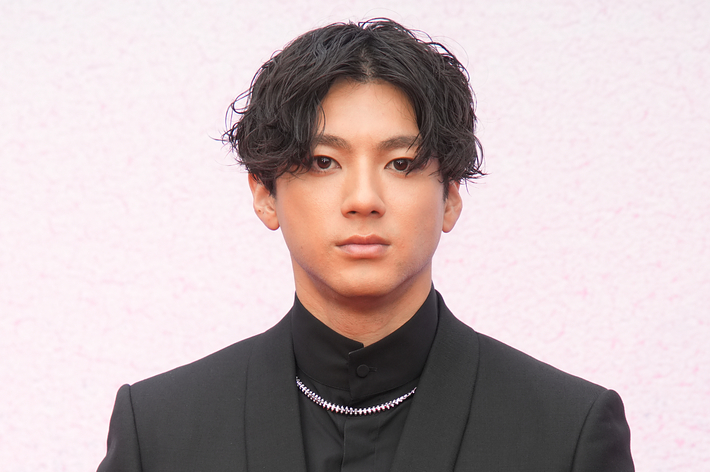 黒いスーツを着た男性が前を向いて立っています。