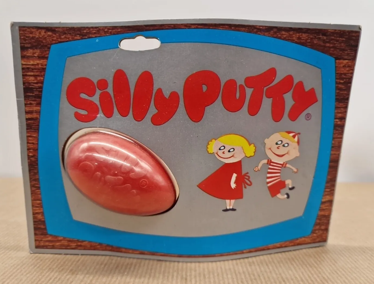 Classic Silly Putty toy packaging featuring a red egg-shaped putty container and cartoon children in 1960s style clothing
