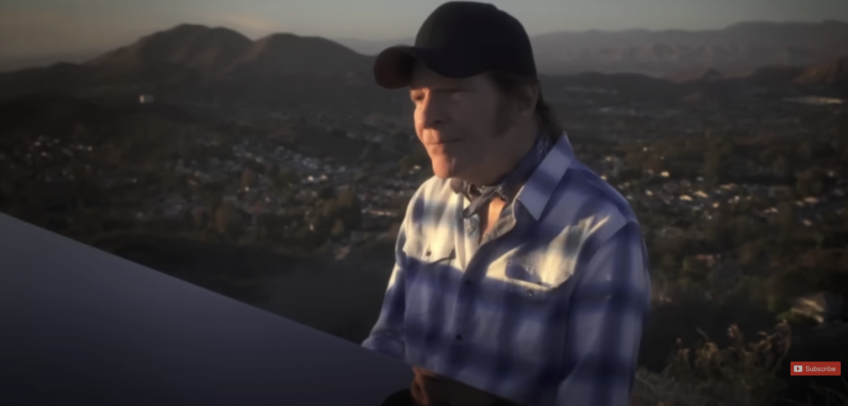 John Fogerty plays the piano outdoors