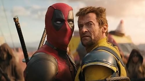 Deadpool (in full costume) and Wolverine (Hugh Jackman) stand closely together in an intense scene, both looking at something off-camera