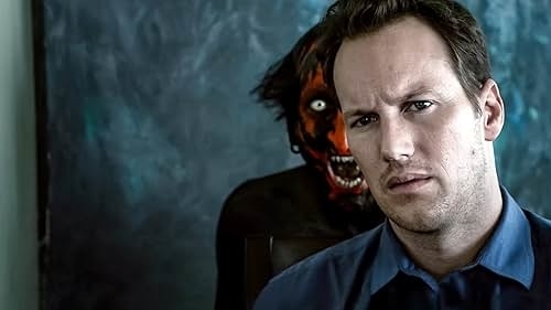 Patrick Wilson stands in the foreground with a worried expression. Behind him is a sinister, red-faced demon figure