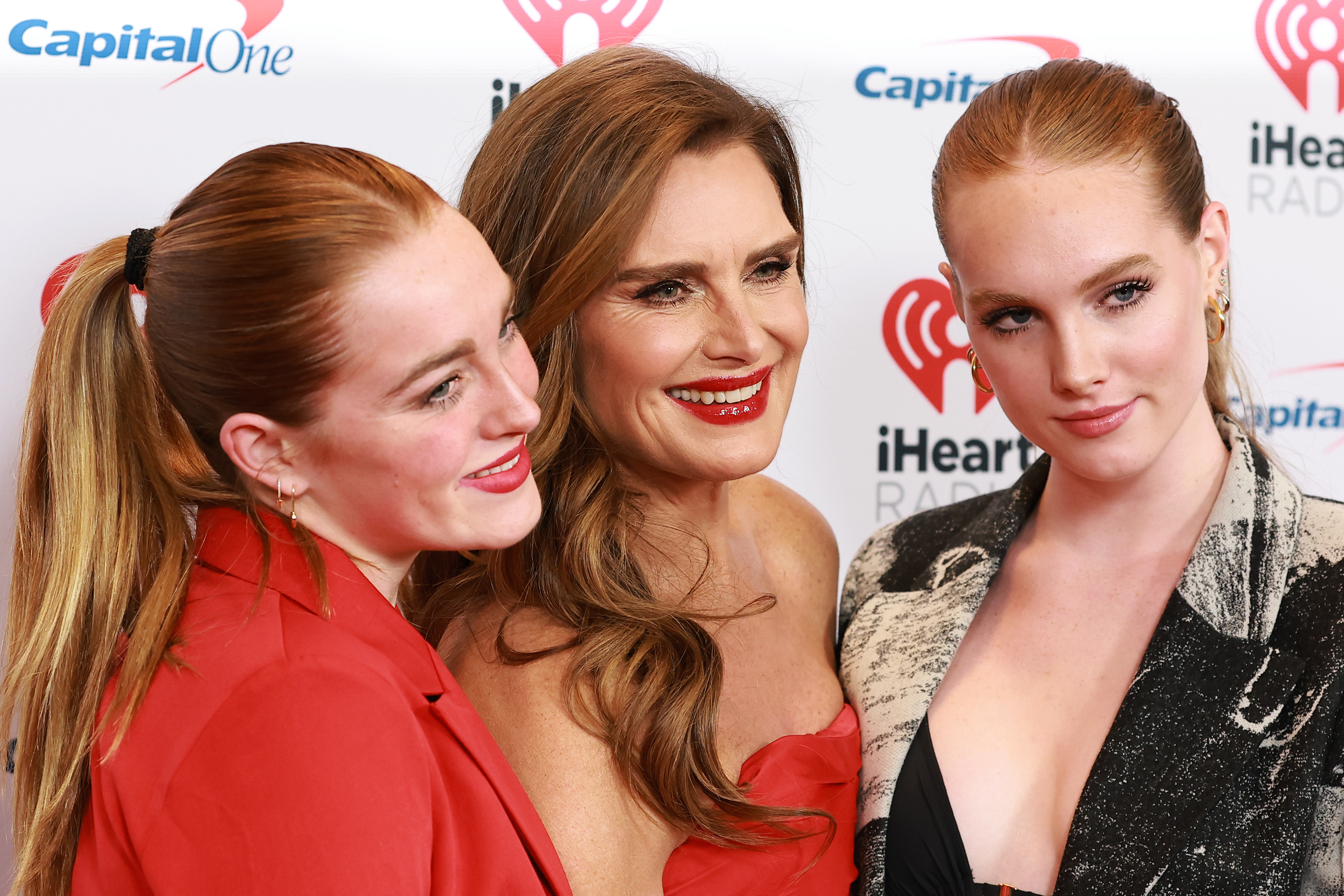 Grier Hammond Henchy, Brooke Shields, and Rowan Francis Henchy at the iHeartRadio event. Brooke wears a strapless dress, while Grier and Rowan wear stylish jackets